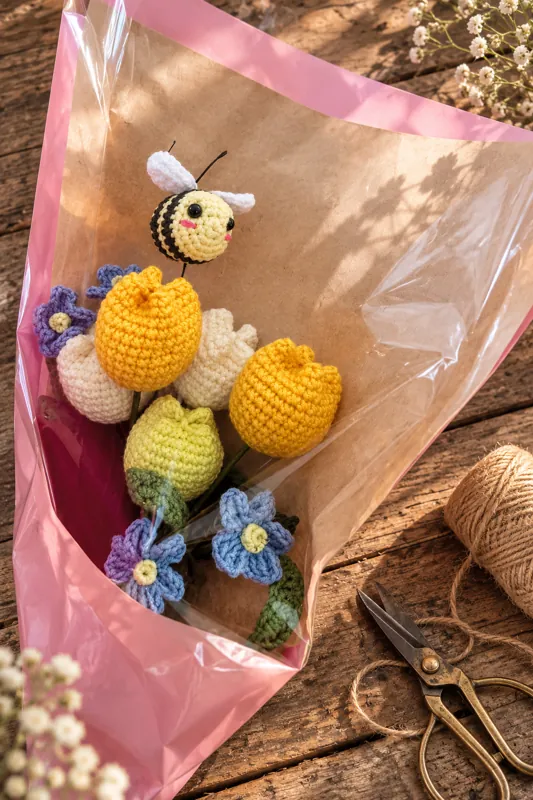 A bouquet of crocheted spring tulips and a small bee, on kraft paper